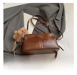 Sac bandoulière rétro marron avec breloque ours en peluche et sangle sur tissu gris