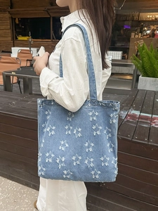 Blue denim tote bag featuring white frayed star patterns and a large capacity casual design