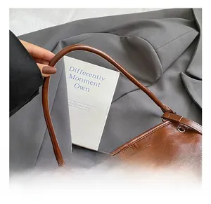 Détails d'un sac à main en cuir marron brillant avec poignée ronde et logo en métal