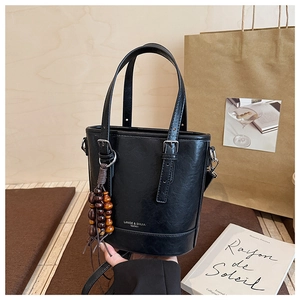 Detailansicht einer schwarzen Beuteltasche mit Markenlogo und Holzperlen-Deko