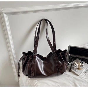 Détail du sac cabas marron foncé brillant avec cordons latéraux et œillets en métal