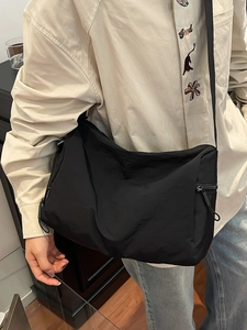 Minimalist black nylon crossbody bag with adjustable strap and fashion label detail