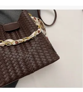 Close-up of dark brown woven shoulder bag featuring a cherry print silk scarf on gold chain