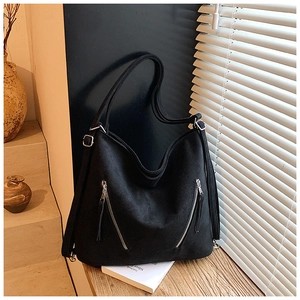 Détail du sac hobo en daim noir avec deux fermetures éclair argentées et des glands