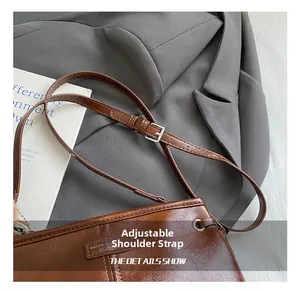 Détail de la bandoulière réglable avec boucle argentée sur un sac à main rétro marron