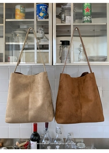 Große beige und braune Wildleder-Einkaufstaschen an Haken in einer Küche aufgehängt
