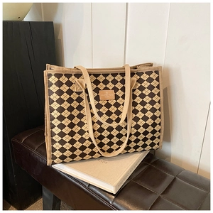 Close-up of checkered canvas tote bag showing brown leather patch and durable woven handles
