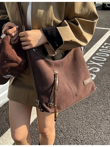 Brown suede tote bag with contrast stitching shown on a model in an outdoor setting