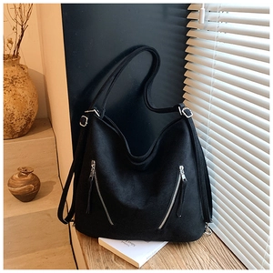 Vue détaillée d'un sac cabas noir mat avec zips argentés sur un rebord de fenêtre en bois