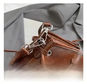 Détail du crochet en métal argenté et coutures premium sur sac à main en cuir marron