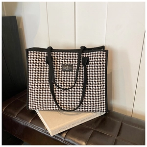 Detail of black and white houndstooth tote bag with leather patch and reinforced handles