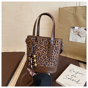 Detail einer Beuteltasche mit Leopardenmuster, Holzperlen-Quaste und Ledergriff