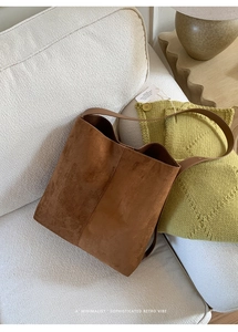 Detailaufnahme der braunen Wildledertasche mit Ziernaht auf weißem Sofahintergrund