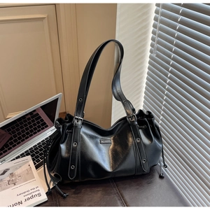 Detail of black PU leather tote bag featuring drawstring closure and metal brand logo