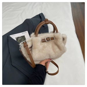 Nahaufnahme der beigen Kunstfell-Handtasche mit braunen Lederriemen und Metallbeschlägen