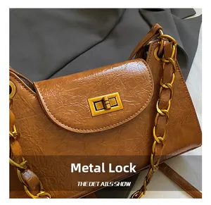 Detail showing vintage brown textured leather bag with gold square metal lock and chain