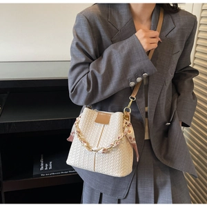 Detail of cream woven bucket bag with silk scarf metal handle and leather strap