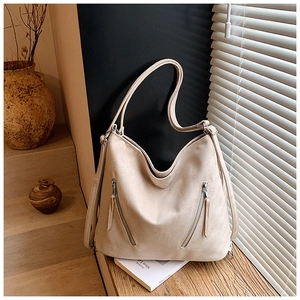 Détail du grand sac cabas beige en daim mat avec deux fermetures éclair verticales de style