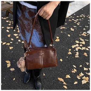 Sac à bandoulière vintage en cuir marron avec breloque ours sur fond de feuilles d'automne