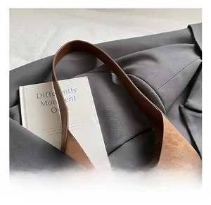 Detail of brown animal texture bucket bag placed on a grey suit with a white book