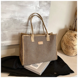 Detailed view of houndstooth weave texture and leather patch on large tote bag