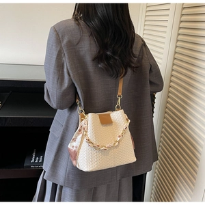 Detail of woven bucket bag with silk scarf handle and leather strap on a model