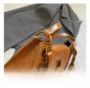 Detail of caramel brown glossy wrinkled leather bag with gold square twist lock and chain