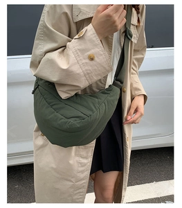 Detail of dark green quilted puffer crossbody bag worn with a casual beige trench coat