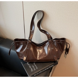Detail of dark brown glossy leather tote bag with adjustable metal eyelet straps