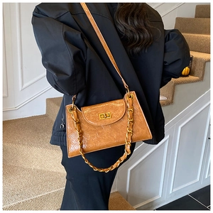Detail of tan wrinkled leather bag with bold gold chain and twist lock on a shoulder bag