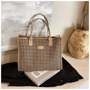 Detail of checkered canvas tote bag with premium leather patch and soft beige handles