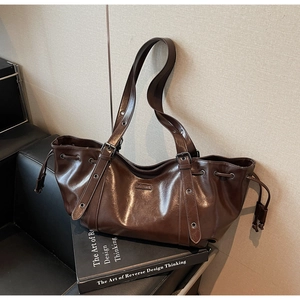Detailed macro view of dark brown glossy wax leather shoulder bag with buckle straps