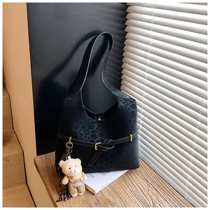Detail of black leopard print hobo bag with a cute teddy bear charm and gold metal buckle