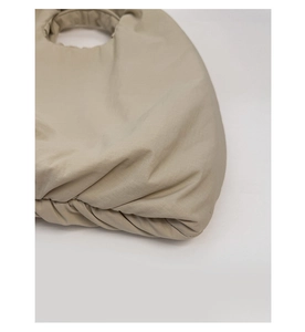 Detail shot of the beige pleated tote bag showing the cross-textured fabric and handle