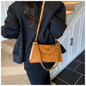 Detailed shot of caramel textured shoulder bag with gold chain and metal twist lock