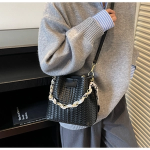 Close-up of black woven bucket bag with silk scarf handle and chain strap detail