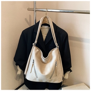 Vue détaillée du grand sac cabas beige en daim avec fermetures éclair sur un blazer