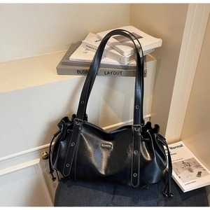 Detail of glossy black leather tote bag with pleated design and silver eyelet strap accents