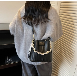 Detail of hand-woven black bucket bag with patterned scarf detail shown from back view