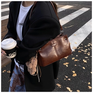 Sac sous le bras marron rétro avec pendentif ours en peluche dans une rue d'automne