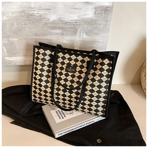 Close-up of black and white checkered tote bag with woven straps and woven brand label