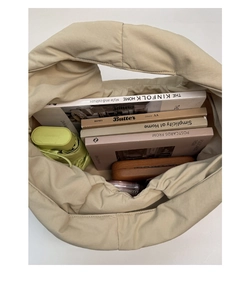 Top view of spacious beige quilted tote bag filled with books and a green folding umbrella