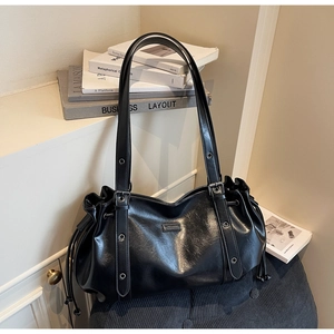 Macro detail of the glossy black tote bag showing side drawstrings and metal eyelets