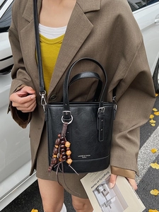 Retro schwarze Beuteltasche mit Litschi-Textur und Holzperlen-Quasten in der Hand