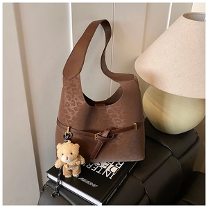 Detailed view of brown leopard print bucket bag with metal buckle and teddy bear charm