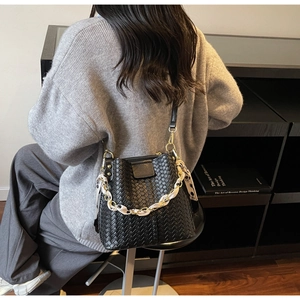 Detail of black woven bucket bag with gold hardware and printed silk scarf on chain