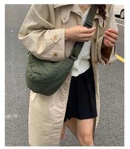Street style shot of dark green nylon dumpling bag paired with a khaki trench coat