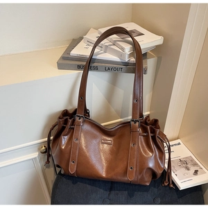 Detail of vintage brown shoulder bag showing soft leather texture and drawstring sides