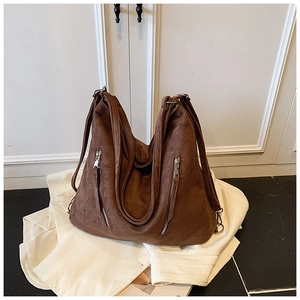 Détail d'un sac cabas en daim marron foncé avec fermetures éclair et texture souple