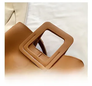 Detail of a brown leather handbag featuring a unique square hollow handle and fine stitching